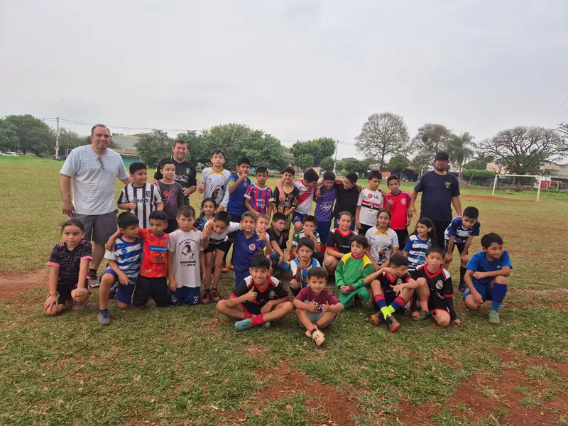 Un complejo deportivo moderno con canchas de pasto sintético iluminadas y una pista de atletismo perimetral.